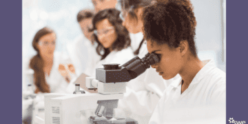Title IX Anniversary cover photo of a women in STEM looking through a microscope