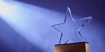 Star shaped SWE awards trophy on a blue background with a spotlight shining on it
