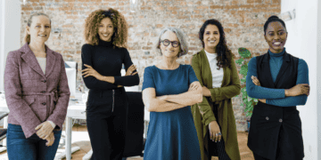 five women engineers in the workplace with a brick wall behind them